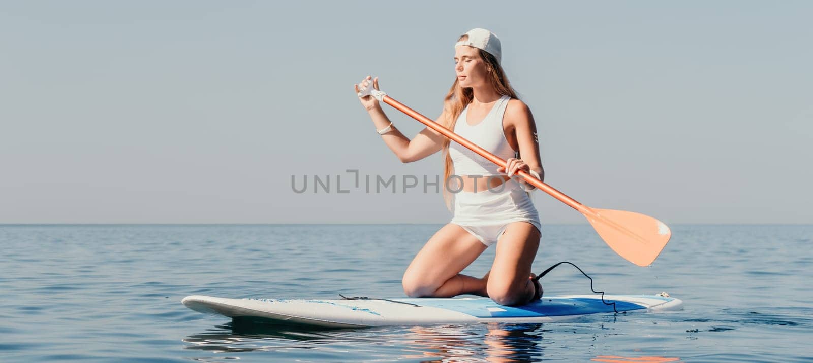 Woman sea sup. Close up portrait of happy young caucasian woman with long hair looking at camera and smiling. Cute woman portrait in bikini posing on sup board in the sea by panophotograph