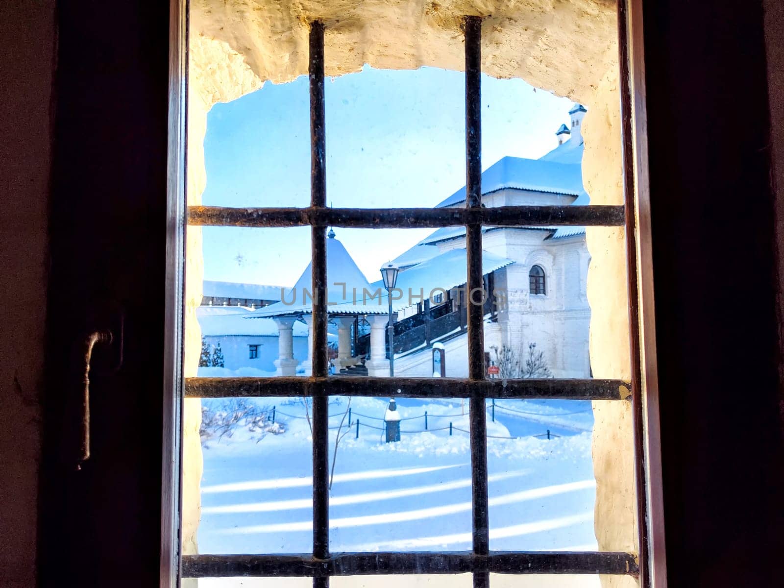 View of the street and the building through the metal grating, grill on window in winter with snow. Abstract Background, pattern, frame