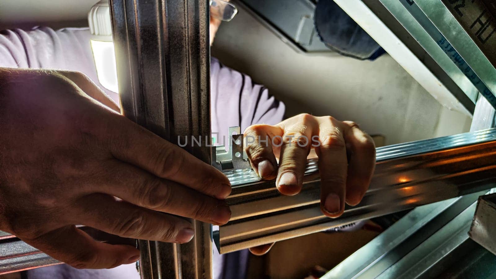 Hand of man with metal plank in hands. Worker do iron construction in dark place