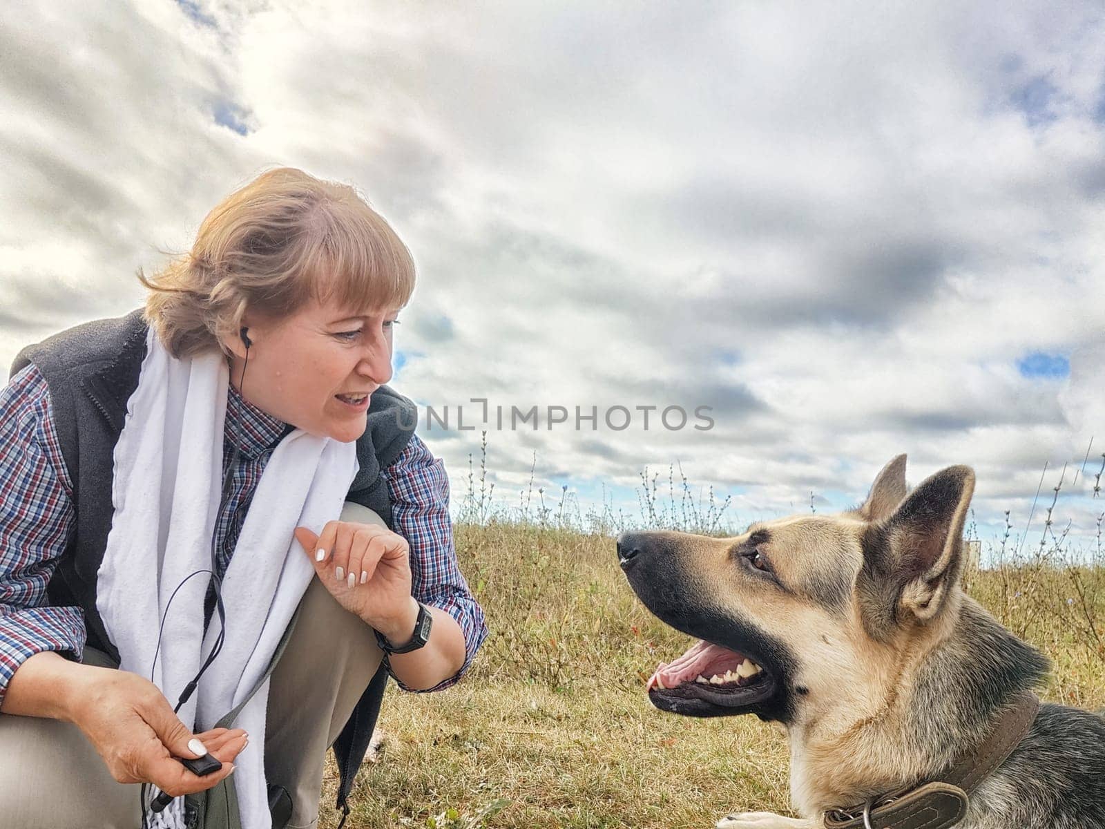 Adult girl with shepherd dog taking selfies in field. Middle aged woman and big shepherd dog on nature. Friendship, love, communication, fun, hugs