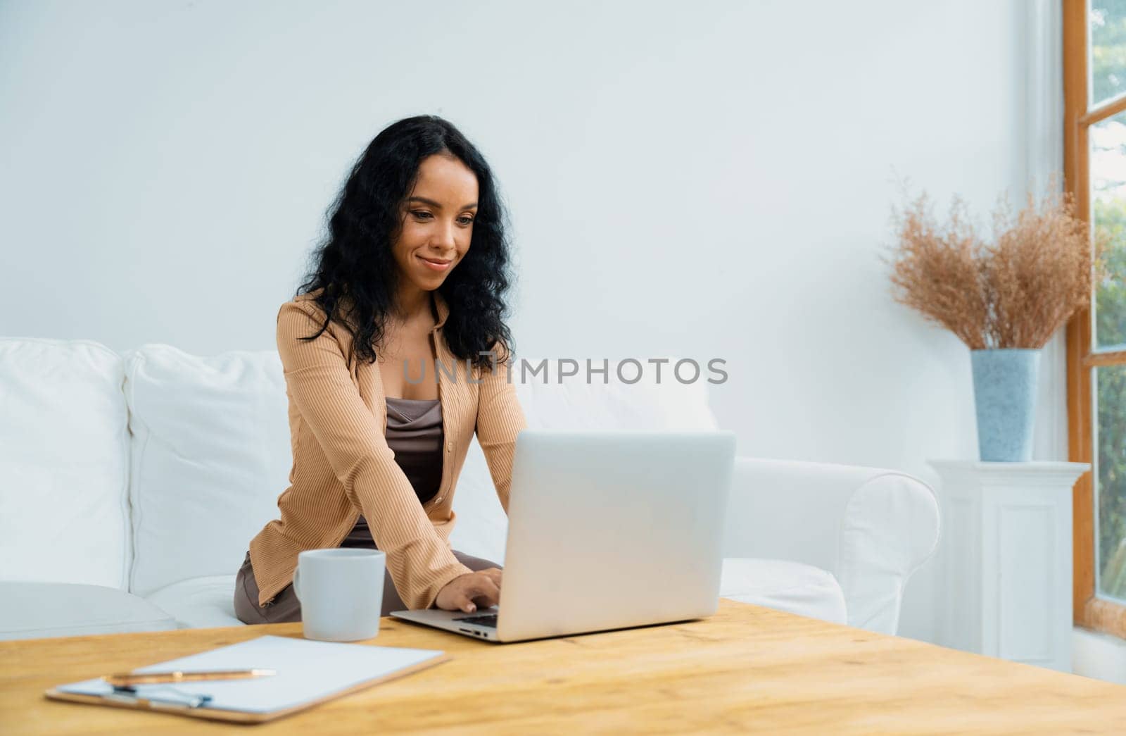 African-American woman using laptop computer for crucial work on internet. Secretary or online content writing working at home.