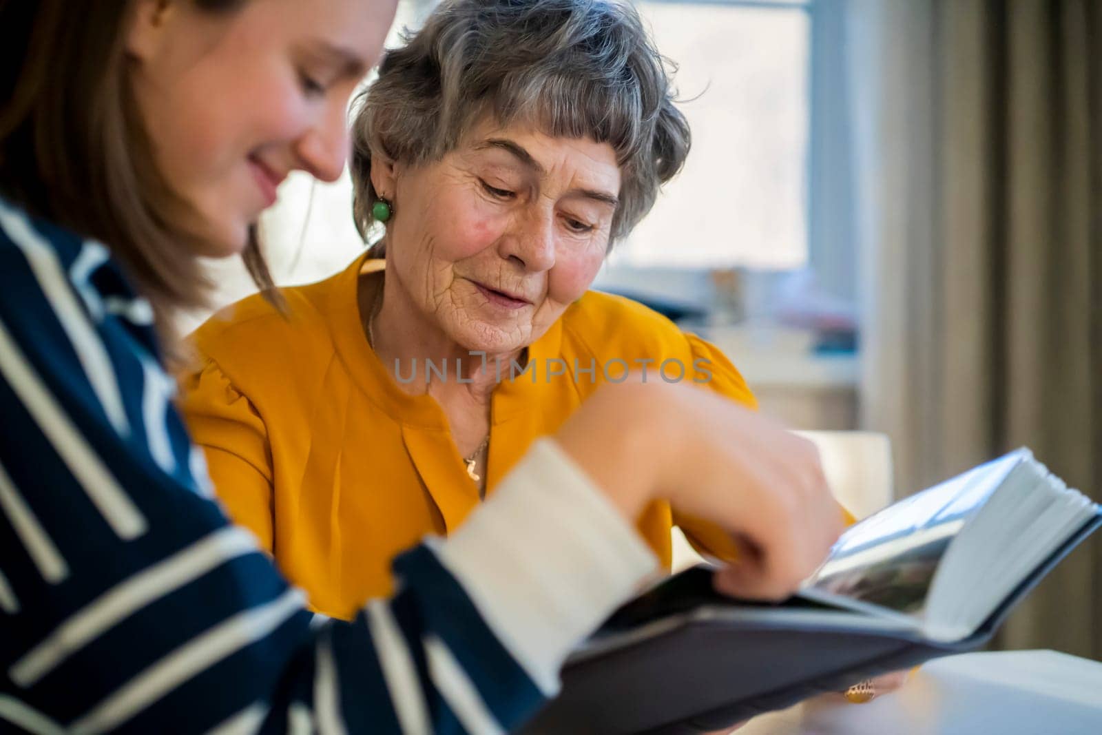 Grandmother and her young granddaughter spent great time together, family members look at photos from the youth of an elderly parent, through the pages of the album and recall funny stories from life.