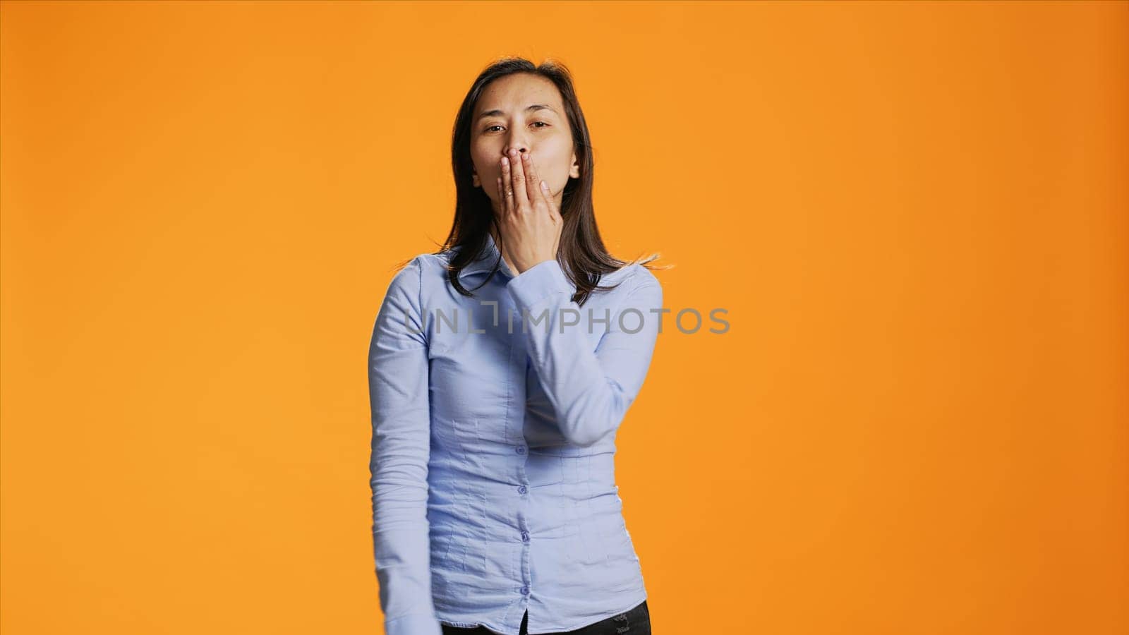 Flirty asian person blowing air kisses in studio by DCStudio