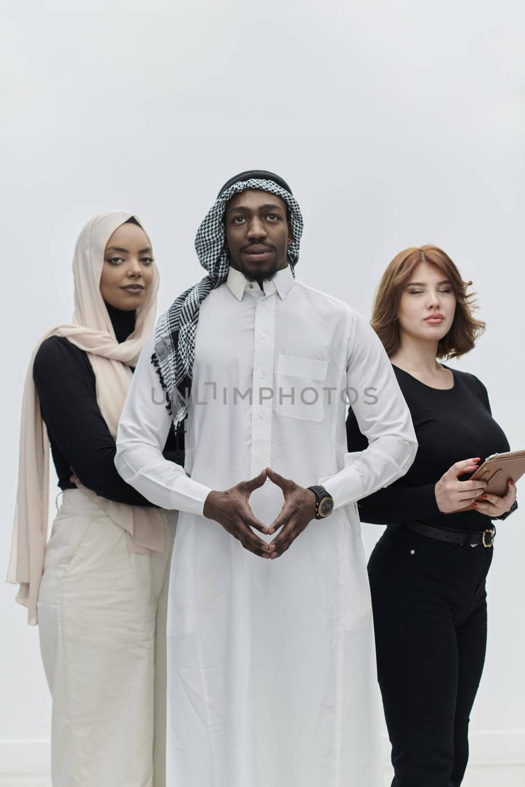 Arabic businessman stands confidently alongside two businesswomen, portraying a poised and diverse team that embodies ambition, innovation, and visionary leadership against a pristine white background.