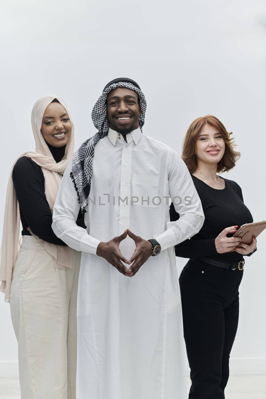 Arabic businessman stands confidently alongside two businesswomen, portraying a poised and diverse team that embodies ambition, innovation, and visionary leadership against a pristine white background.
