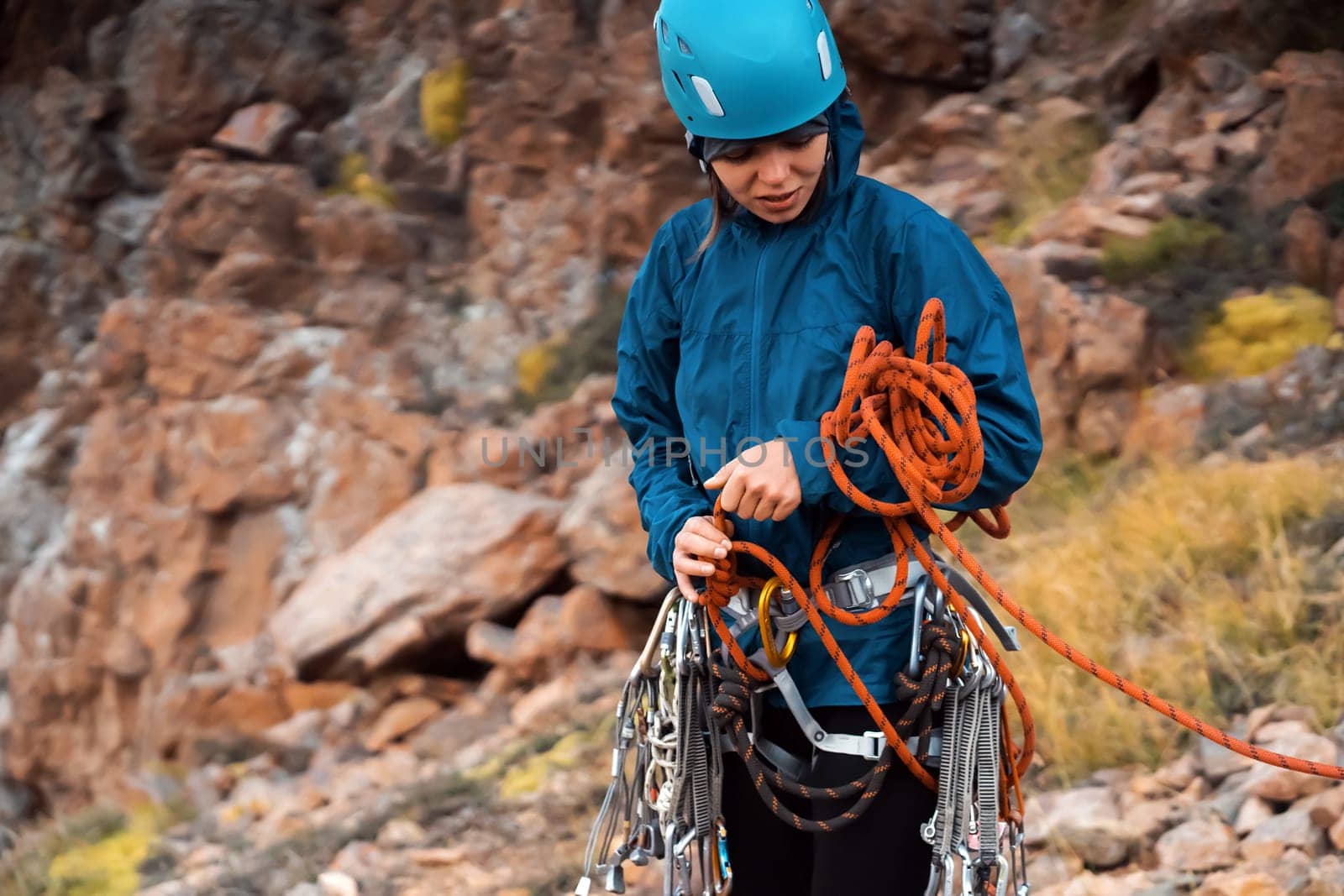 A young girl is mountaineering, checking equipment and straightening the rope before going in a bunch to the top of the mountain.
