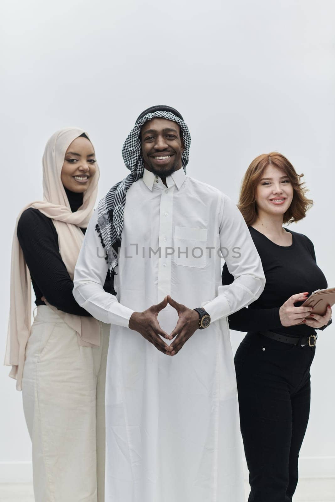 Arabic businessman stands confidently alongside two businesswomen, portraying a poised and diverse team that embodies ambition, innovation, and visionary leadership against a pristine white background by dotshock