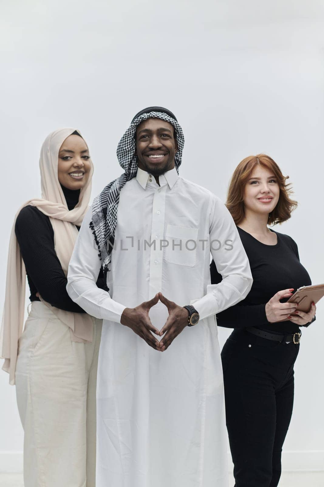 Arabic businessman stands confidently alongside two businesswomen, portraying a poised and diverse team that embodies ambition, innovation, and visionary leadership against a pristine white background by dotshock