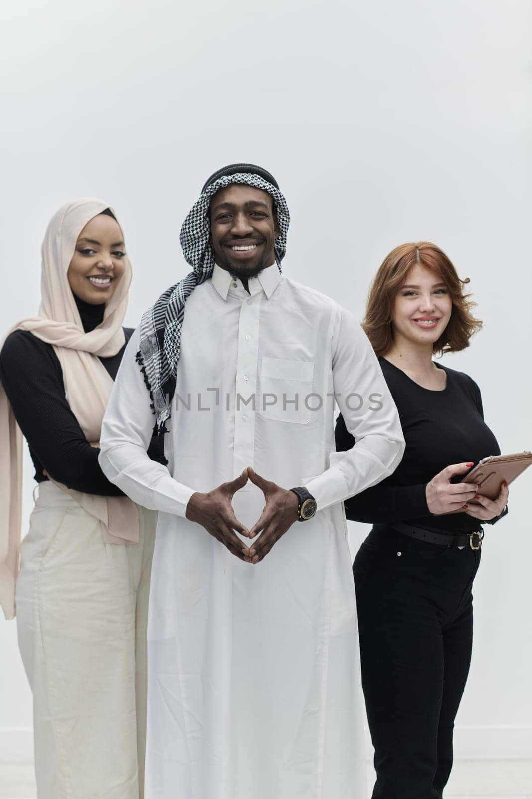 Arabic businessman stands confidently alongside two businesswomen, portraying a poised and diverse team that embodies ambition, innovation, and visionary leadership against a pristine white background.