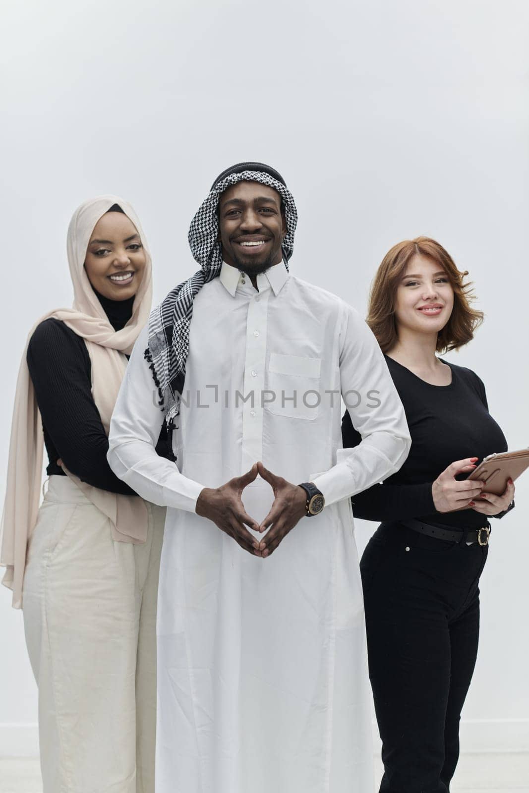 Arabic businessman stands confidently alongside two businesswomen, portraying a poised and diverse team that embodies ambition, innovation, and visionary leadership against a pristine white background by dotshock