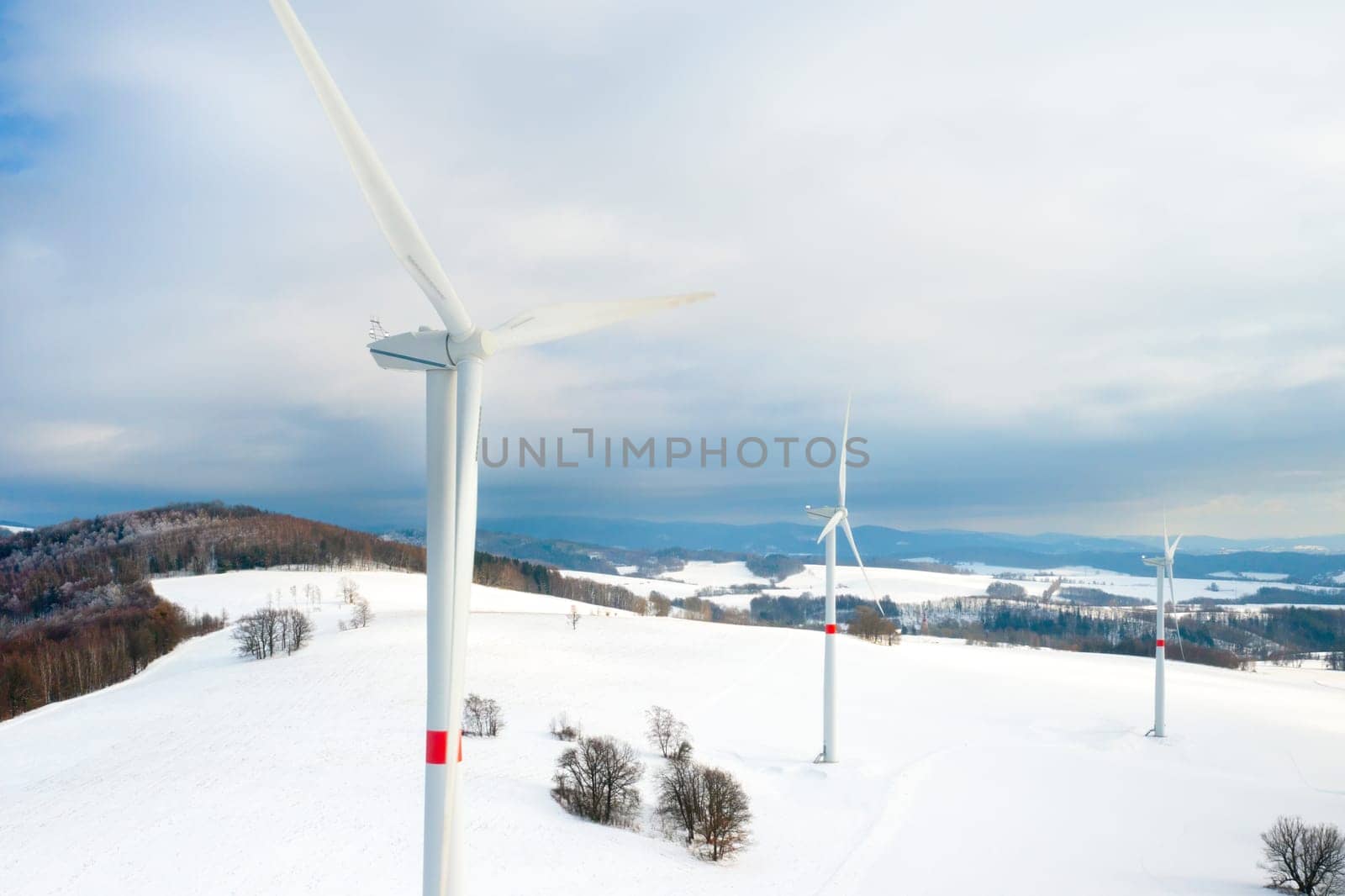 Aerial view of wind turbines or windmills for electricity production in the field in winter. Renewable and green energy concept