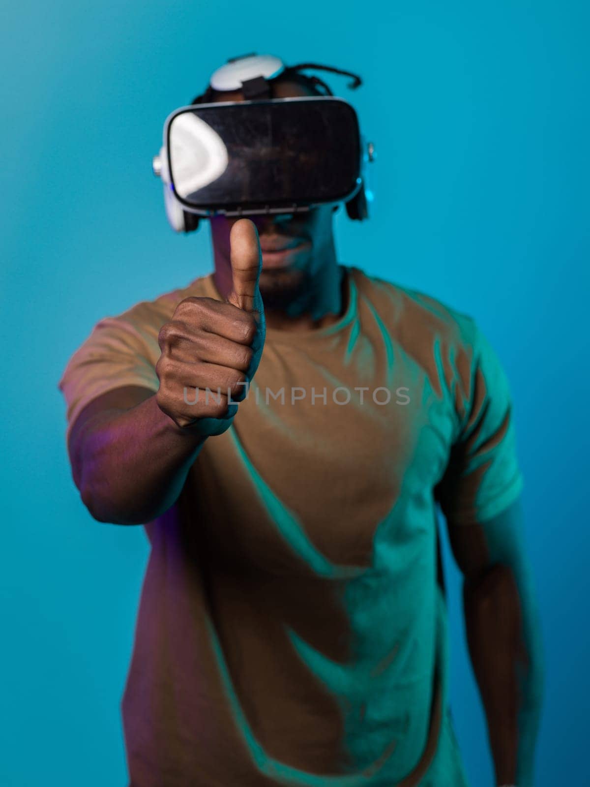 African American man wearing virtual reality glasses expresses satisfaction and impressed delight, gesturing with his hand pointed upward, while standing isolated against a vibrant yellow background, showcasing a positive and contented experience within the immersive virtual realm.