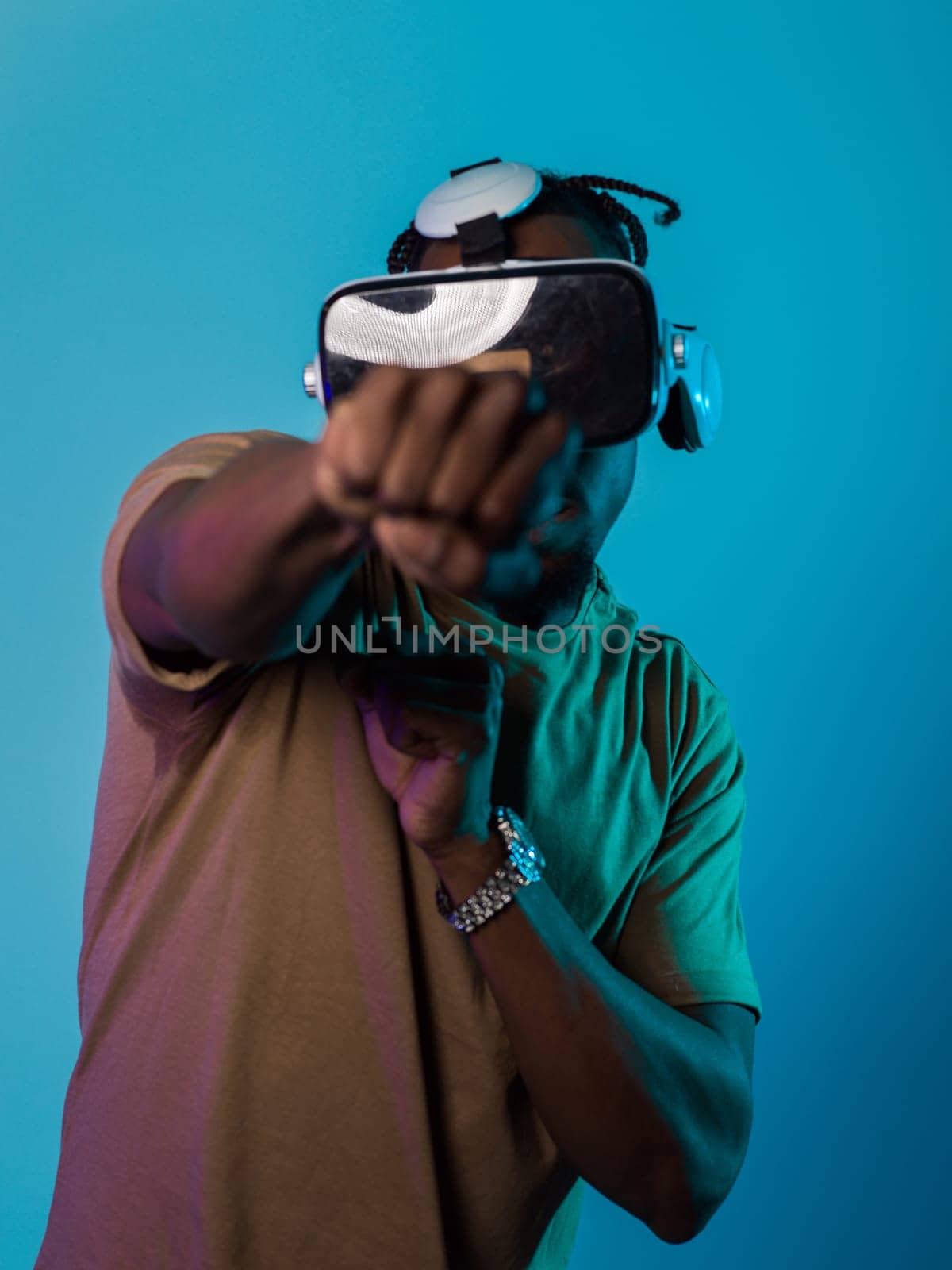 In an avant-garde scene, an African American man engages in cutting-edge virtual reality gaming, utilizing VR glasses to immerse himself in futuristic boxing games, set against a vivid blue background, showcasing the seamless fusion of technology, innovation, and interactive entertainment.