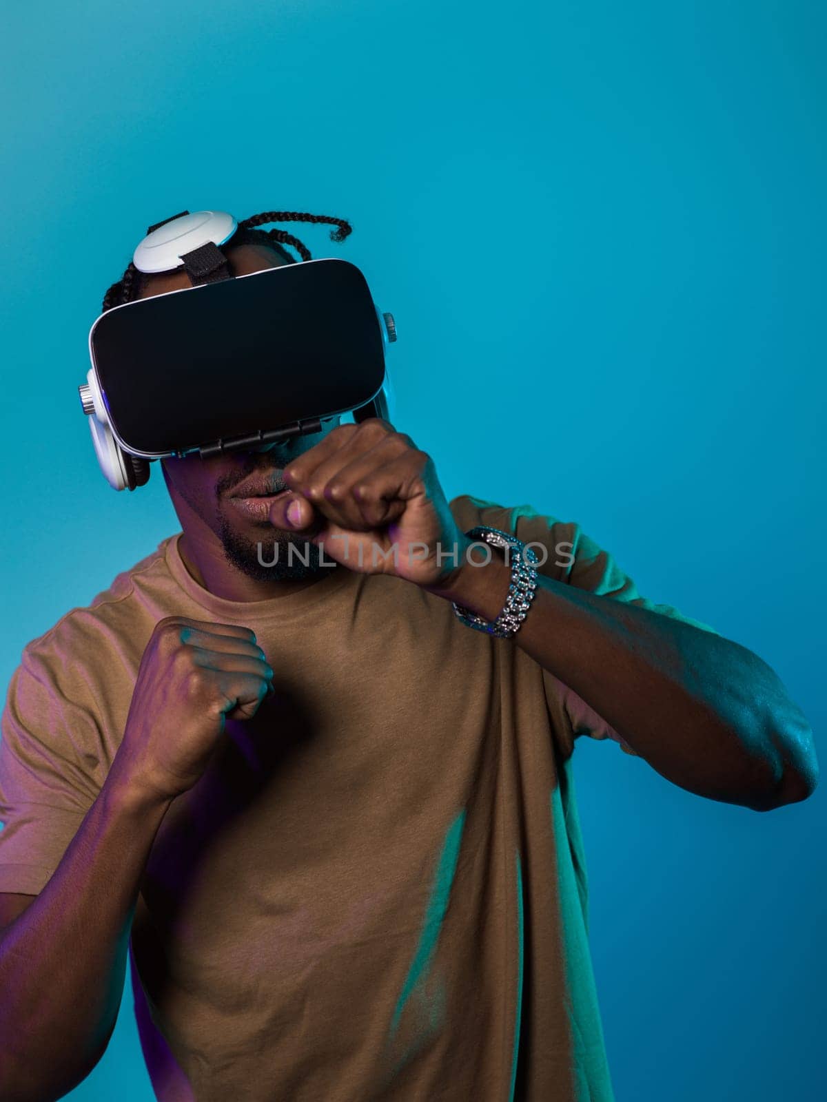 In an avant-garde scene, an African American man engages in cutting-edge virtual reality gaming, utilizing VR glasses to immerse himself in futuristic boxing games, set against a vivid blue background, showcasing the seamless fusion of technology, innovation, and interactive entertainment.