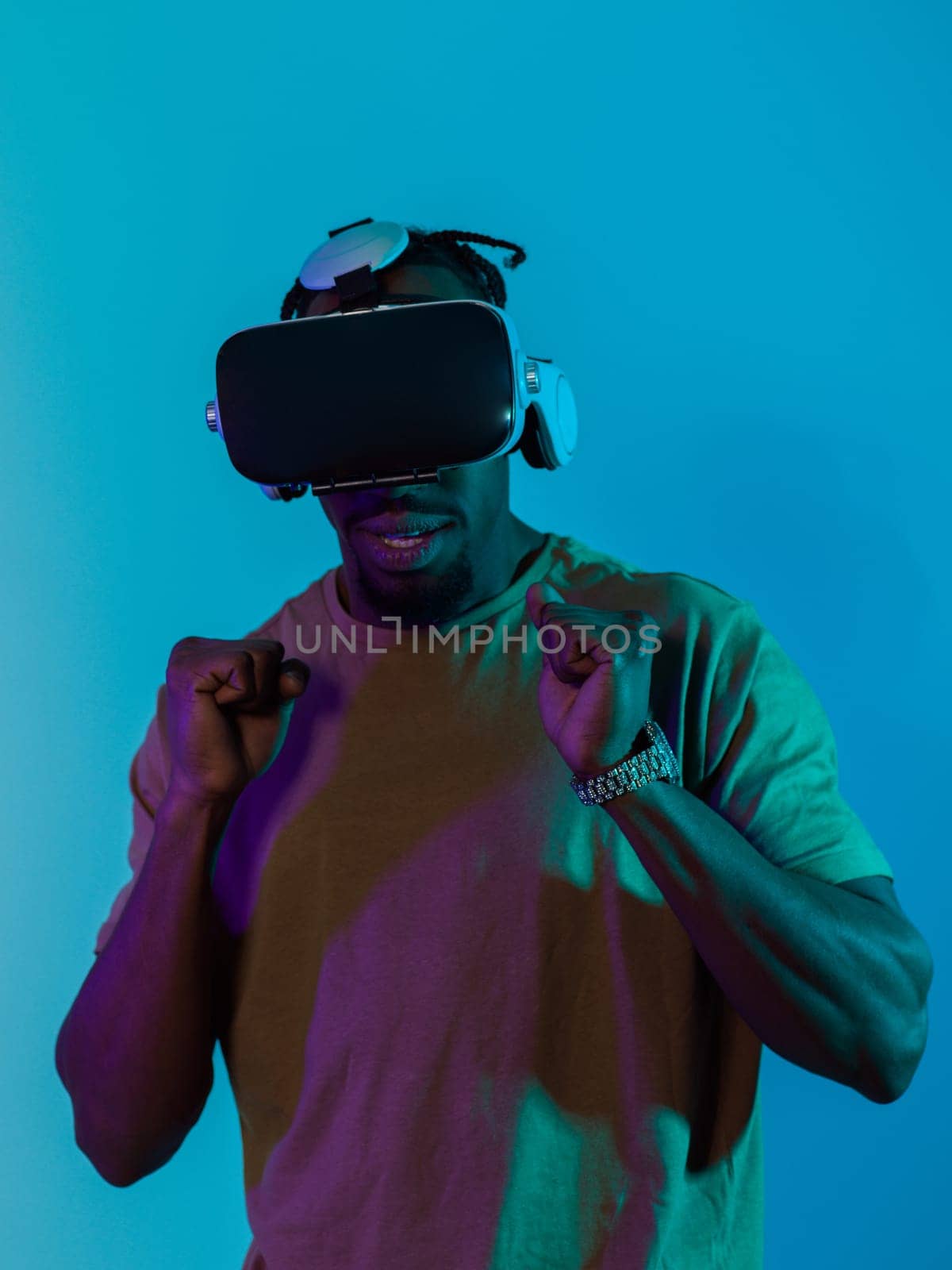 African American man immerses himself in a thrilling horror gaming experience using VR glasses, creating an isolated and intense atmosphere against a striking blue background by dotshock
