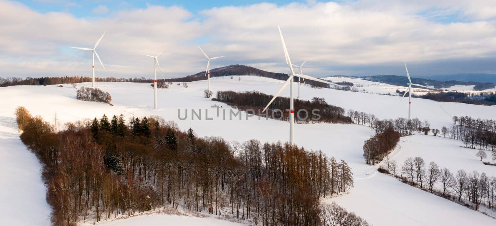 Wind turbine on winter field against cloudy blue sky during sunset. by vladimka