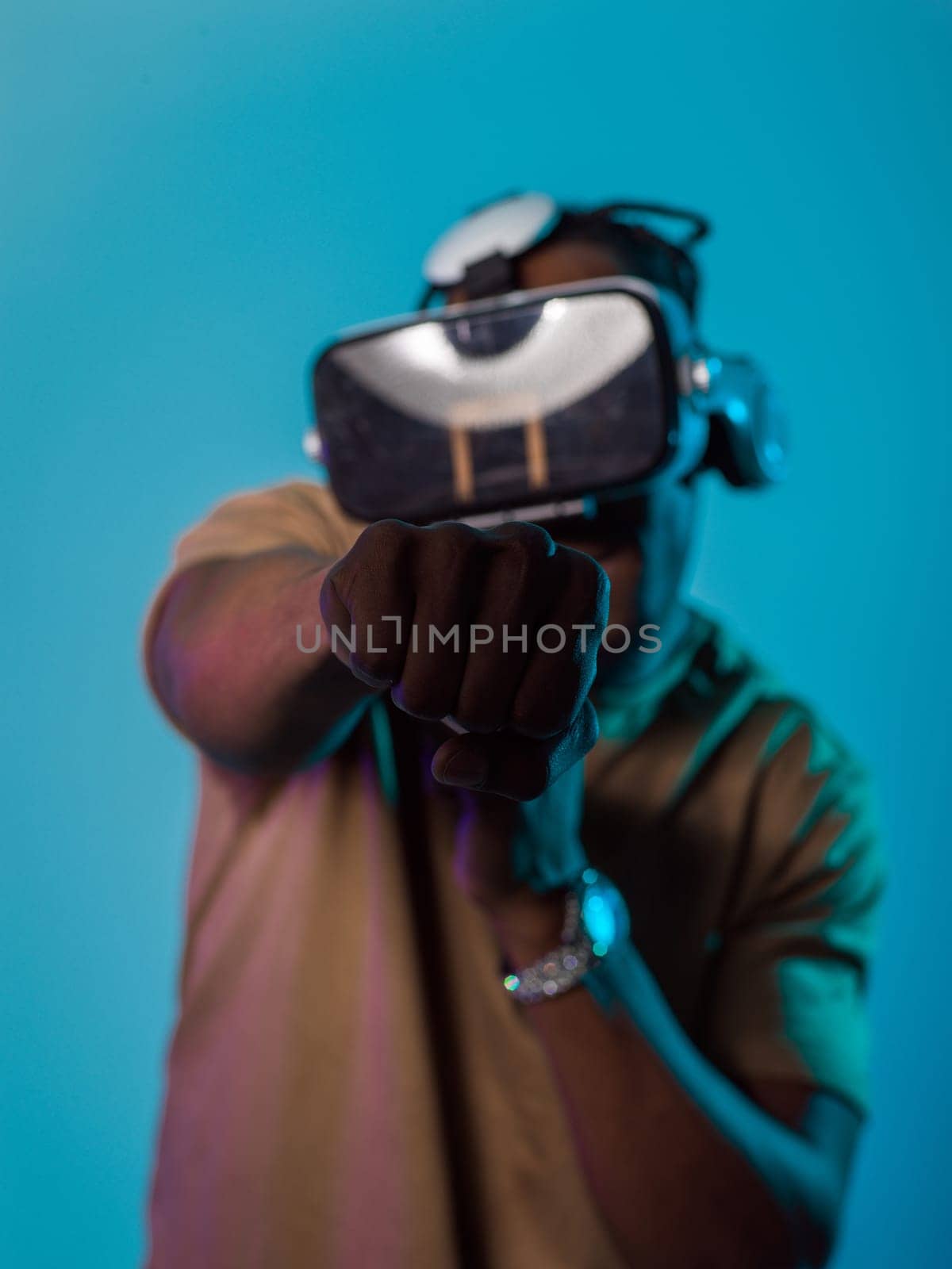 In an avant-garde scene, an African American man engages in cutting-edge virtual reality gaming, utilizing VR glasses to immerse himself in futuristic boxing games, set against a vivid blue background, showcasing the seamless fusion of technology, innovation, and interactive entertainment by dotshock