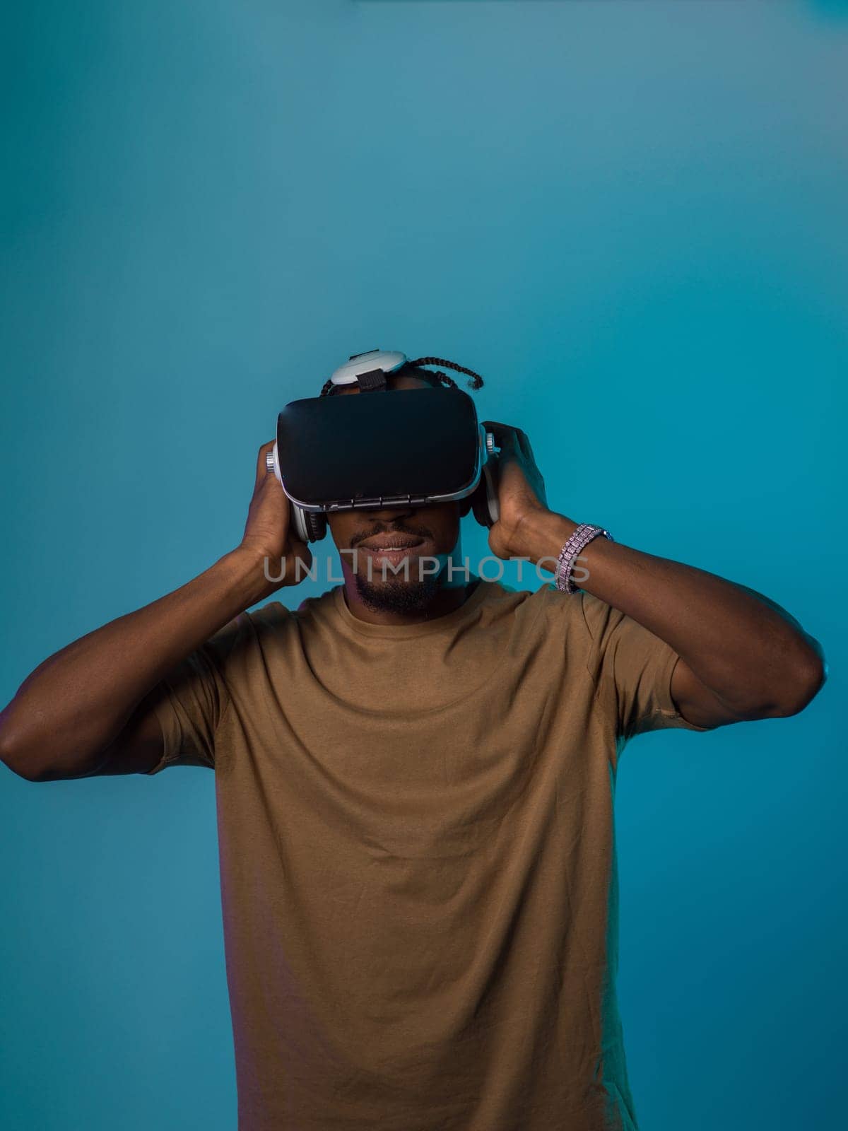 In a futuristic visual, an African American man stands isolated against a striking blue backdrop, adorned with VR glasses that transport him into a cutting-edge virtual reality experience, merging technology and innovation in a contemporary display by dotshock