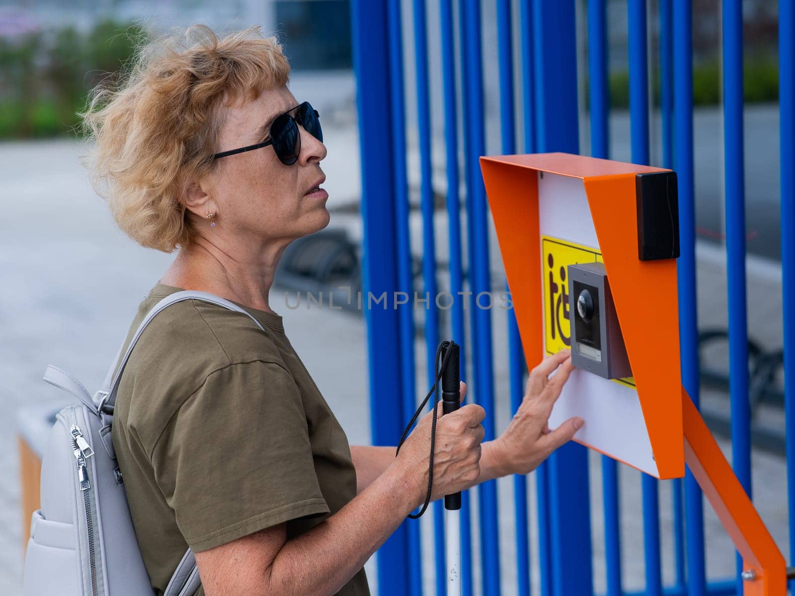 An elderly blind woman reading a text in braille. Button for calling help for people with disabilities