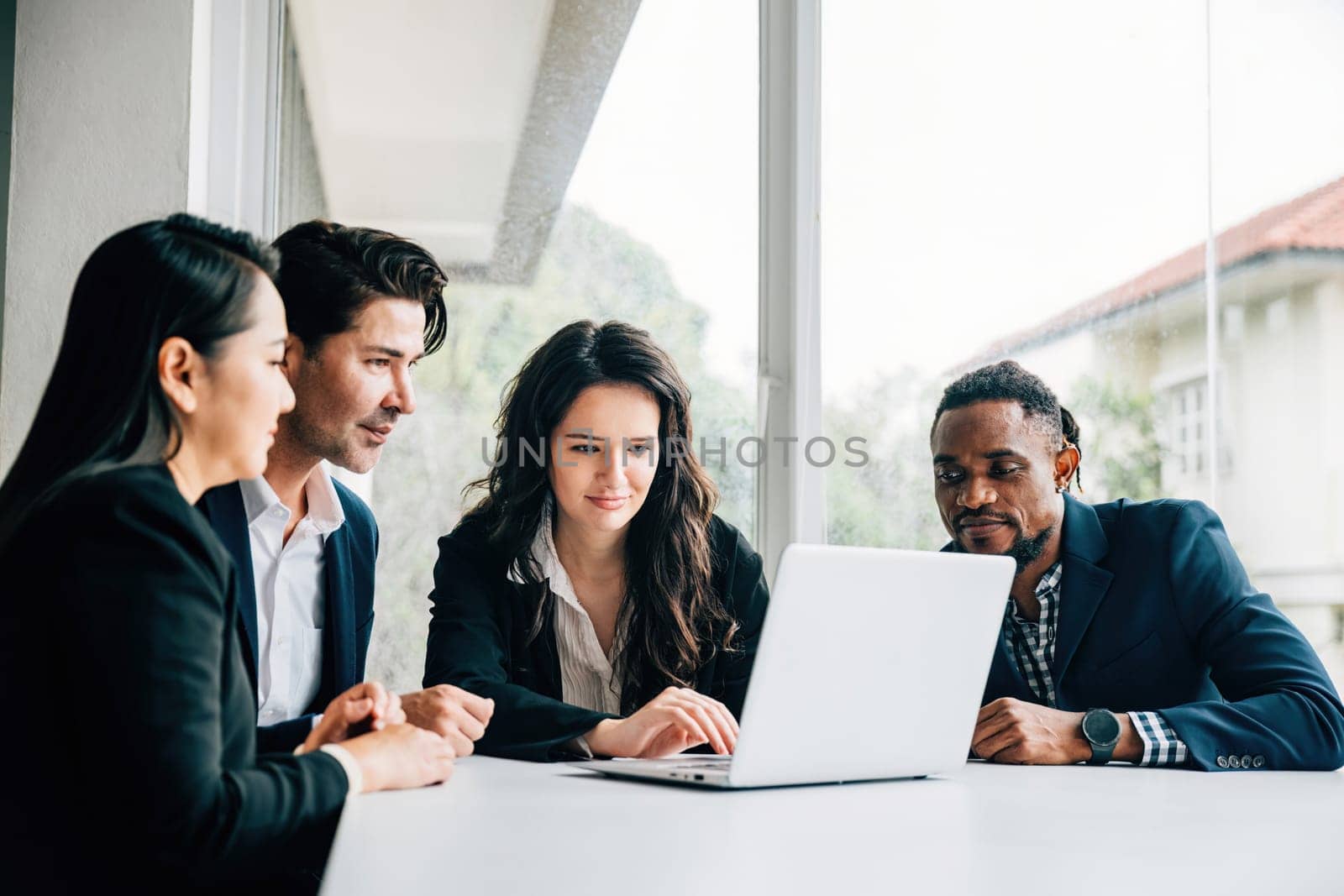 Diverse group of men and women in business collaborates in meeting room use laptop. Their teamwork diversity and cooperation are evident they engage in discussion planning and strategizing for success by Sorapop
