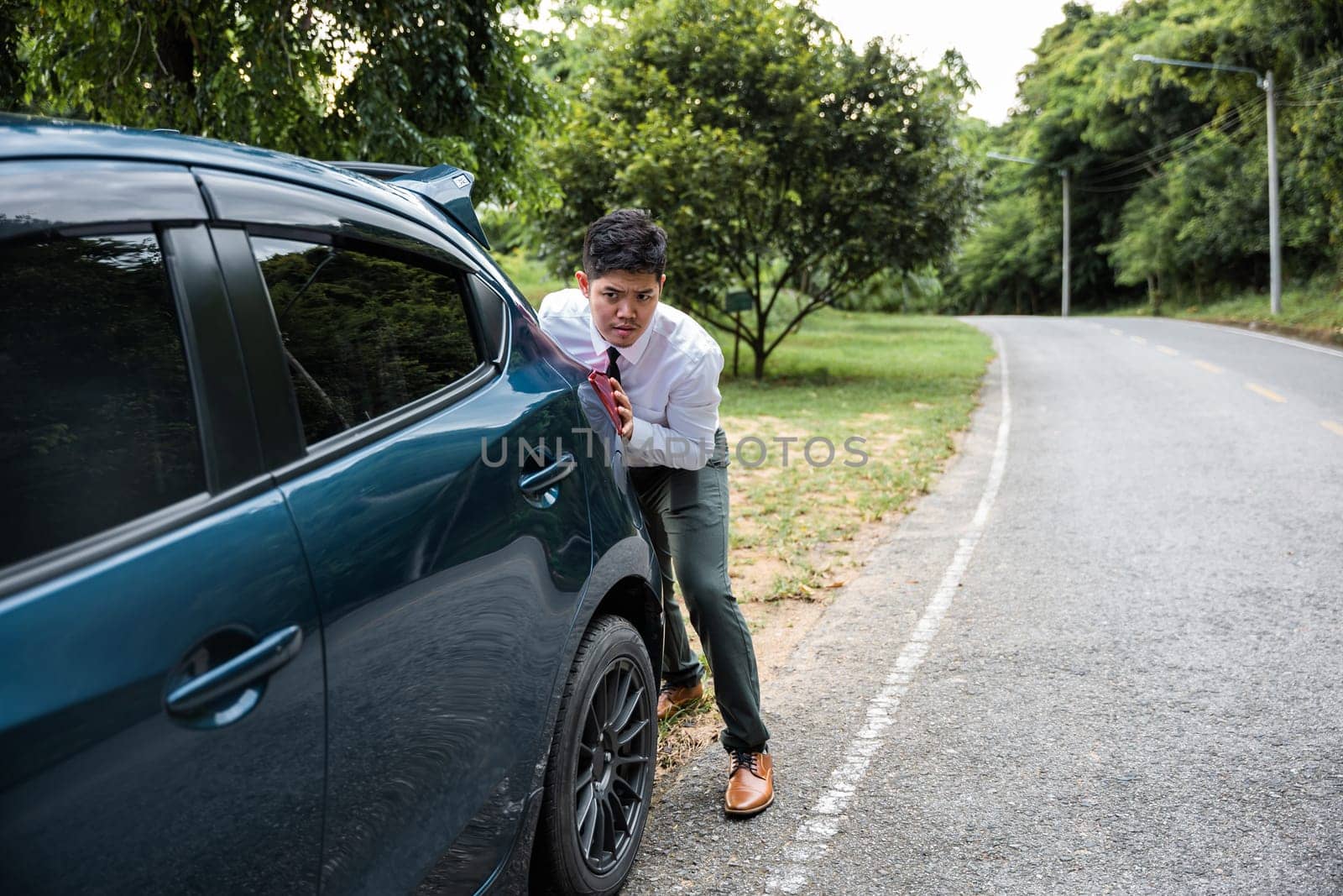 Asian businessman car broken has problems with car down during go to work in morning he pushing out of gas on road at countryside, business man have trouble roadside, problem transportation