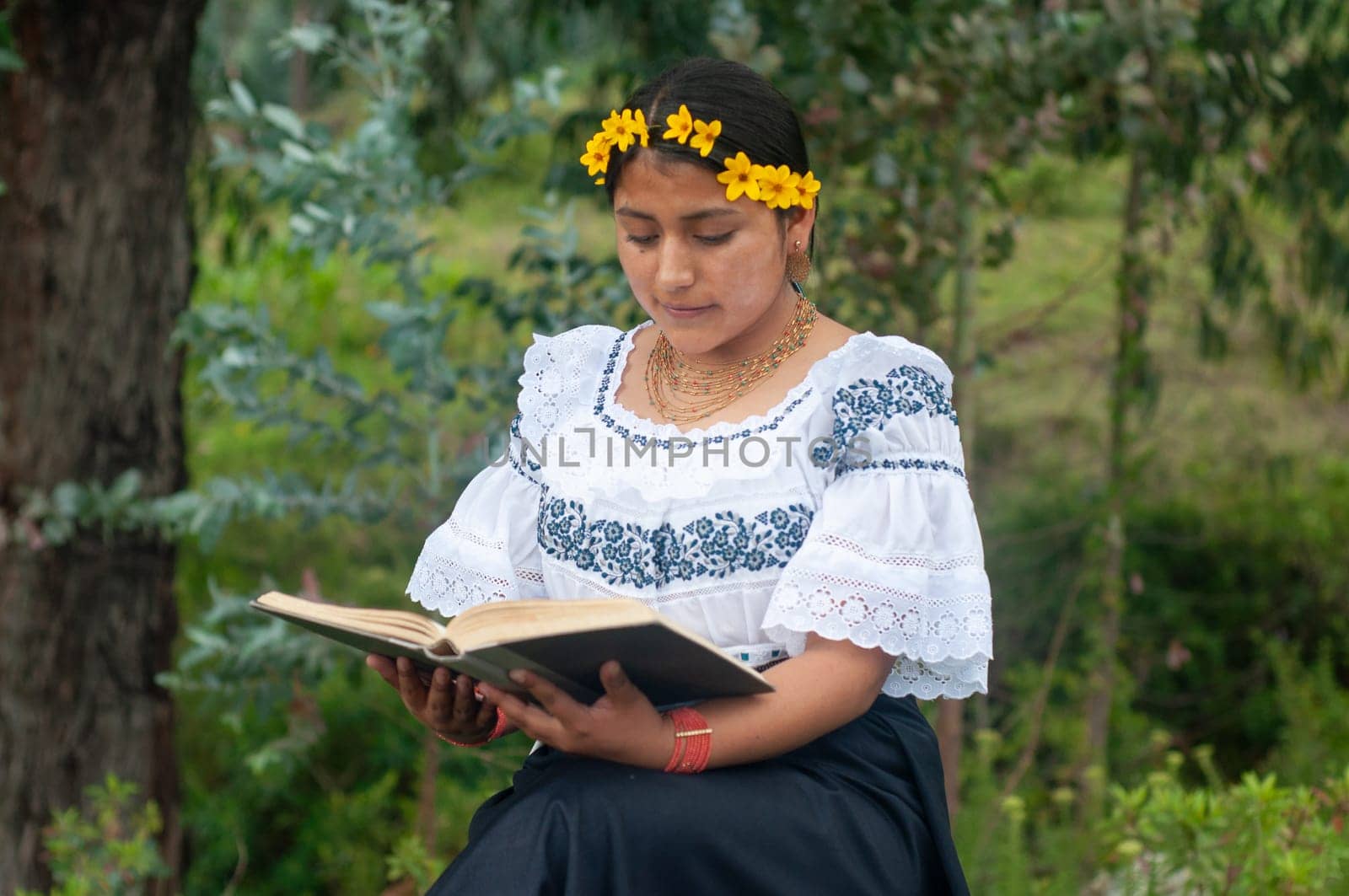 A captivating image of a woman in a flowing dress, completely engrossed in reading an unidentified book.