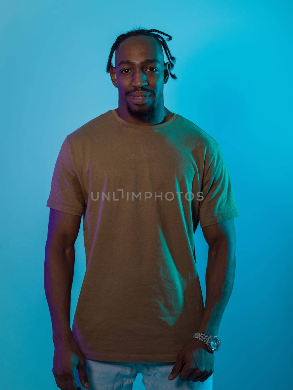 African American man with a modern and sophisticated hairstyle stands confidently against a vibrant blue backdrop, showcasing a blend of contemporary fashion and cultural identity with elegance and charisma.