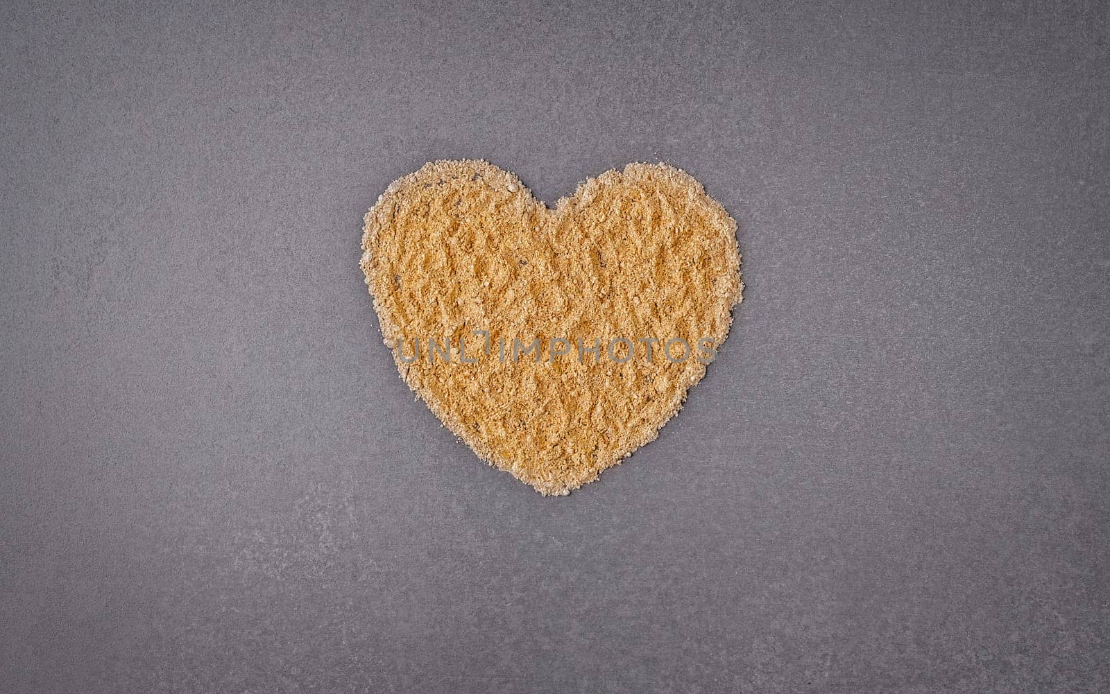 Top view of golden powder heart shape on gray background with copy space by NataliPopova