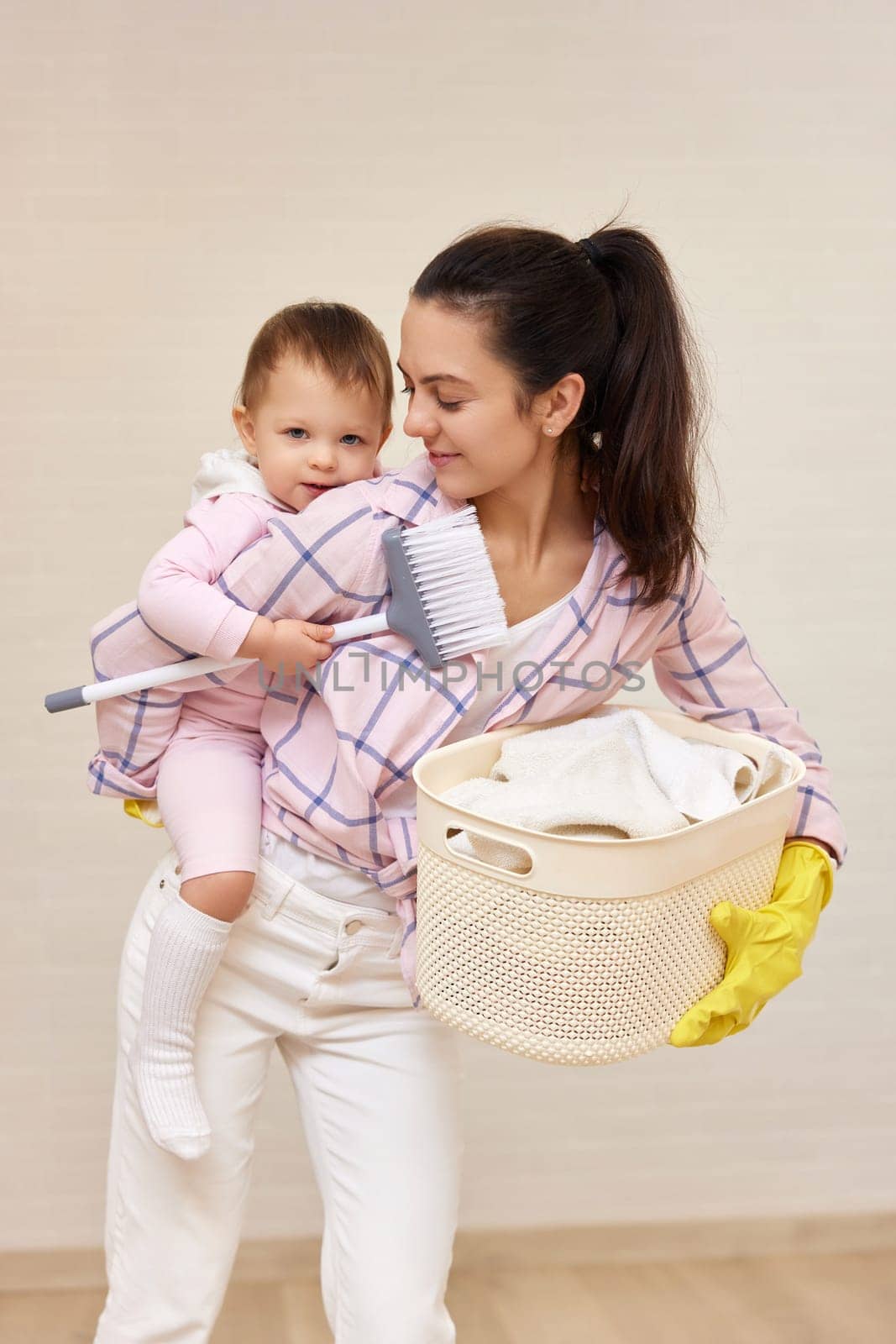 happy mother housewife is holding cute baby girl and basket with laundry , Happy family