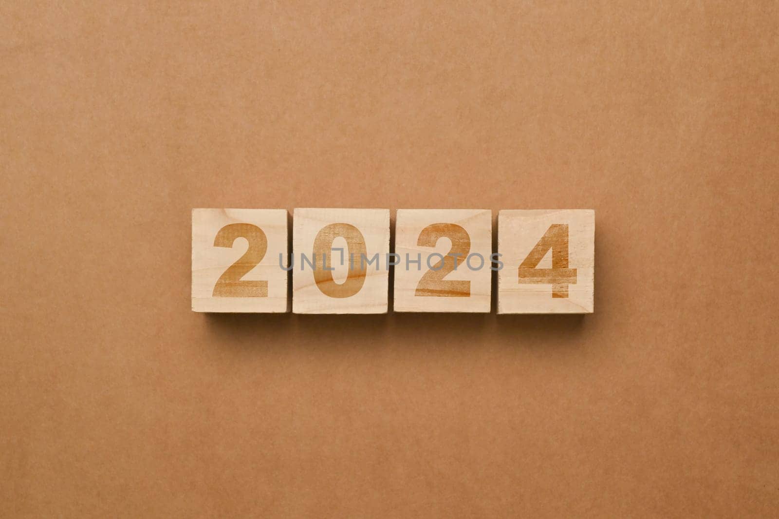 Wooden cube blocks with 2024 on brown background. Start new year goals, plan and visions concept.