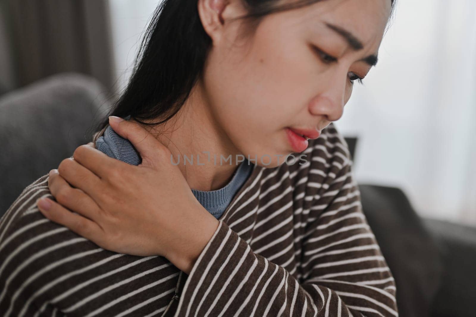 Upset young woman touching neck, suffering from pain and strain. Healthcare and problem concept.