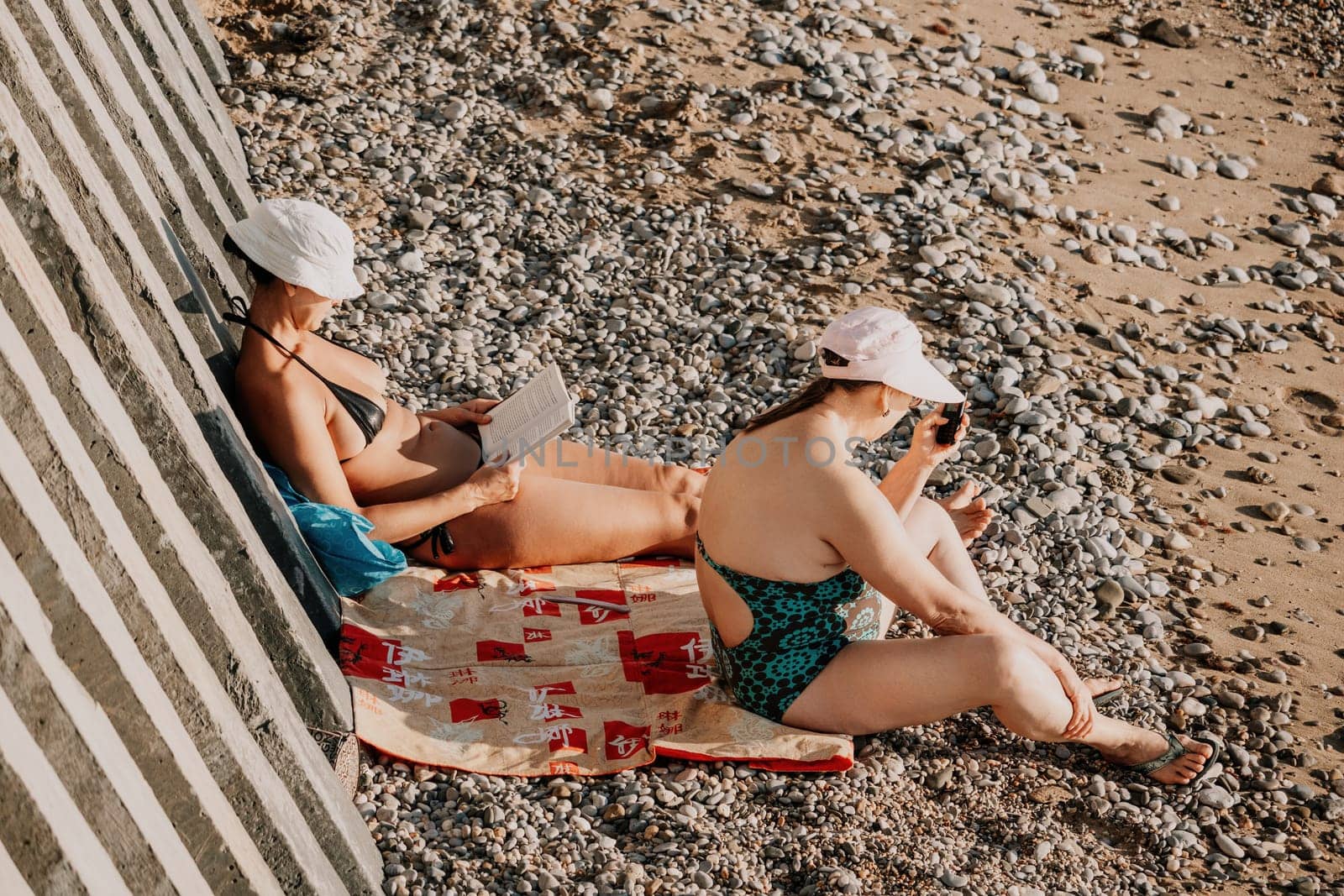 Woman reading book and Sitting on the Beach on Vacation. Summer Holidays Travel Concept. Summer chill. Rest and pleasure. Holidays on the beach. Side view by panophotograph