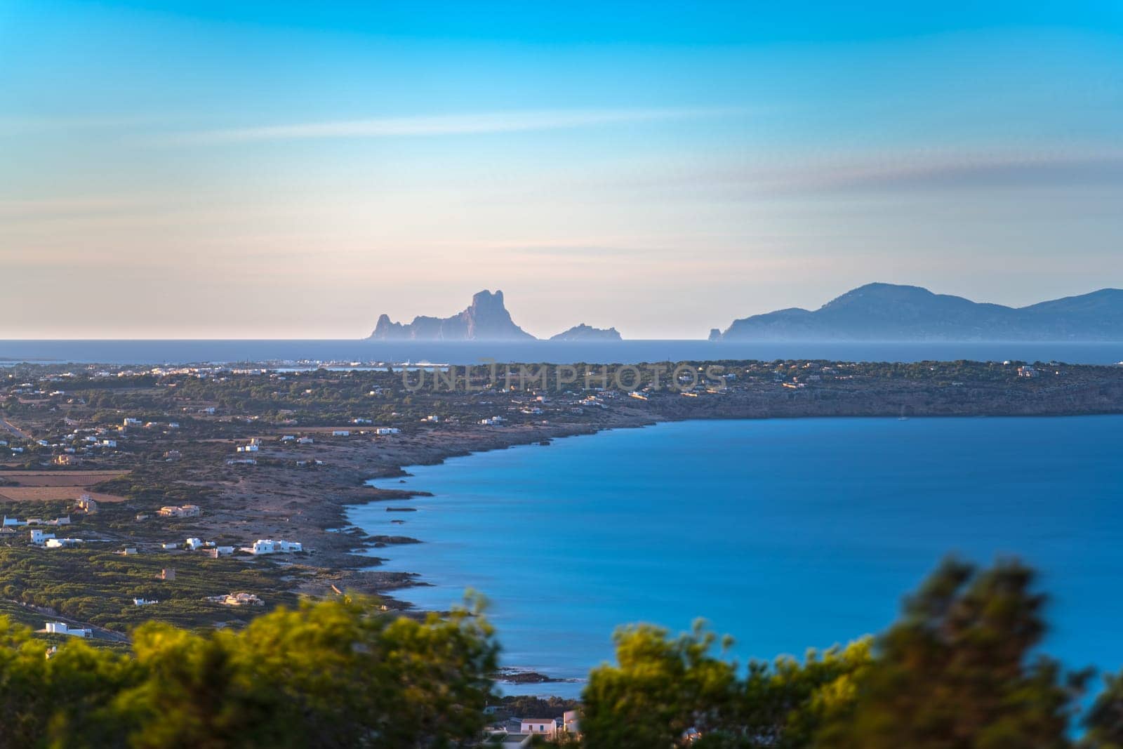Stunning long exposure photo of Formentera Island's clear bay, with Ibiza and Es Vedra silhouetted in the background.