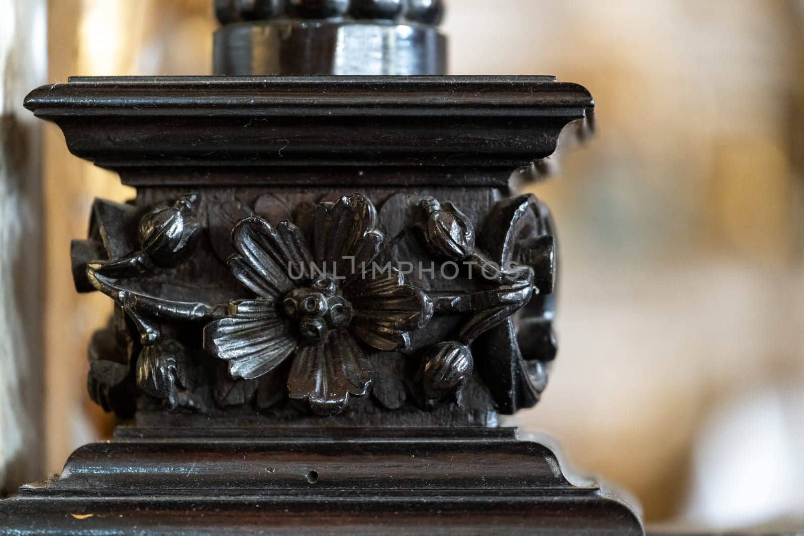 A photo highlighting a detailed wooden flower carving on vintage furniture.