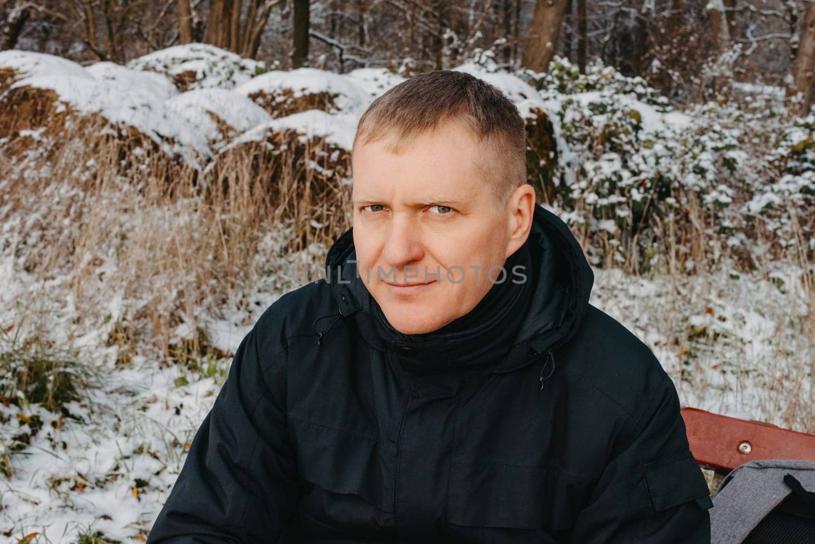 Winter Serenity: 40-Year-Old Man Enjoying Tea on Snow-Covered Bench in Rural Park. Immerse yourself in the tranquil beauty of winter as a 40-year-old man finds solace on a snowy bench in a rural park. by Andrii_Ko