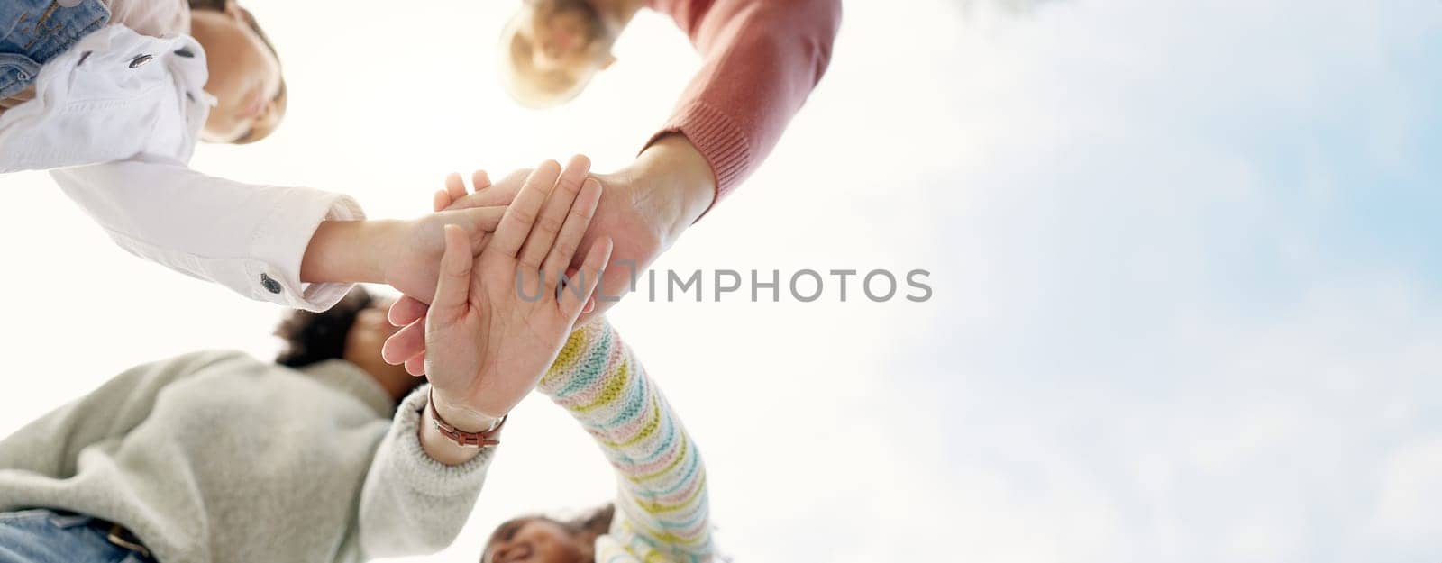 Family, hands together and team in solidarity below for collaboration or celebration under sky. Low angle of mother, father and kids piling for teamwork motivation, support or coordination together by YuriArcurs