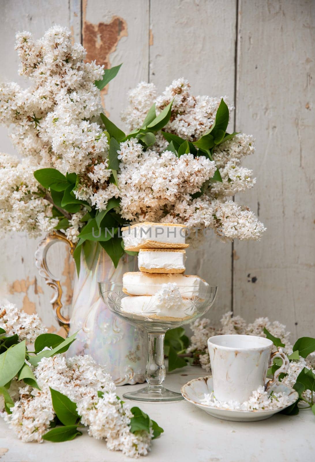 spring still life, a stack of waffle ice cream in a bowl and on a saucer, with a bouquet of white lilacs in an antique ceramic bowl, a cup of aromatic coffee, high quality photo