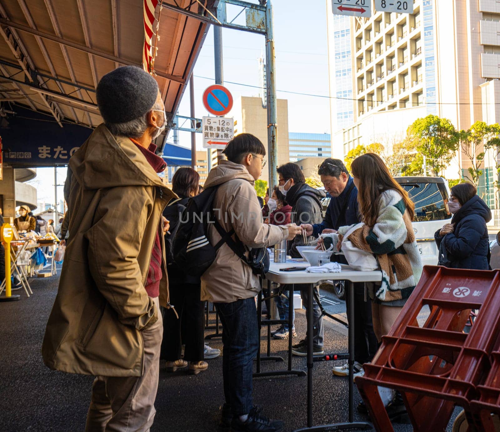 Tokyio, Japan. January 2024.  people eating while standing among food stalls at the Tsukiji Outer Market in the city center