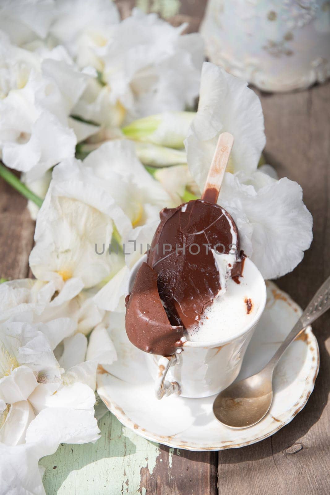 melted chocolate ice cream in a cup of coffee, spring still life with a bouquet of white irises, antique porcelain tableware, romantic break for dessert, top view, high quality photo