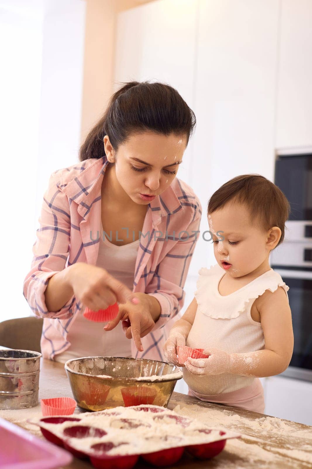 mother and little baby girl baking in the kitchen, bake cookies. happy time together