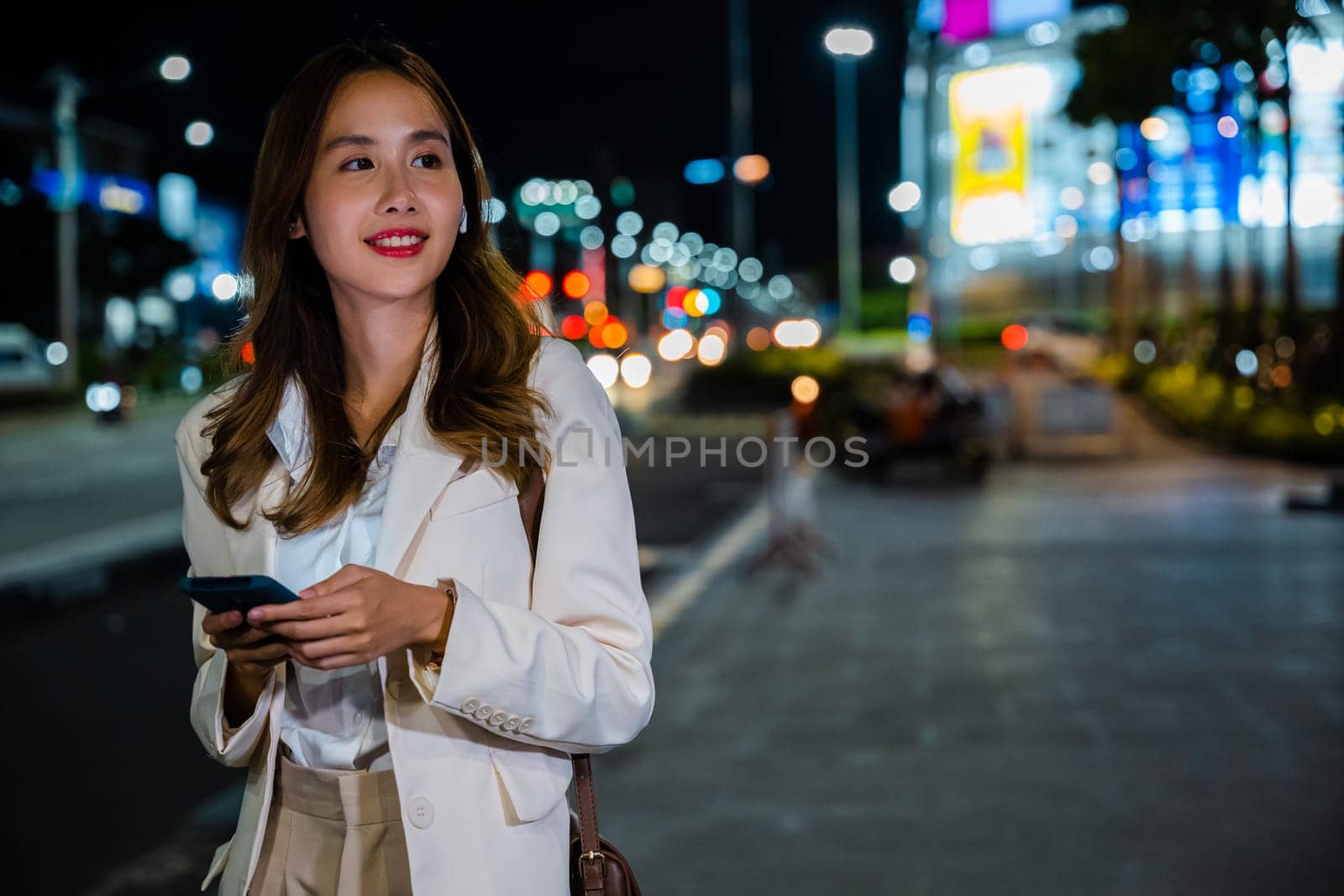 Young woman using modern smartphone in night city by Sorapop