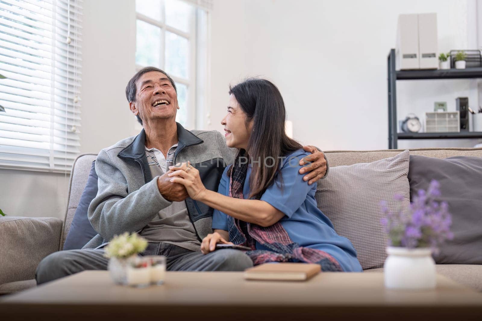 Happy mature husband and wife sit rest on comfortable sofa in living room enjoy talking, smiling elderly couple relax on couch at home chat speak laugh on leisure weekend by nateemee