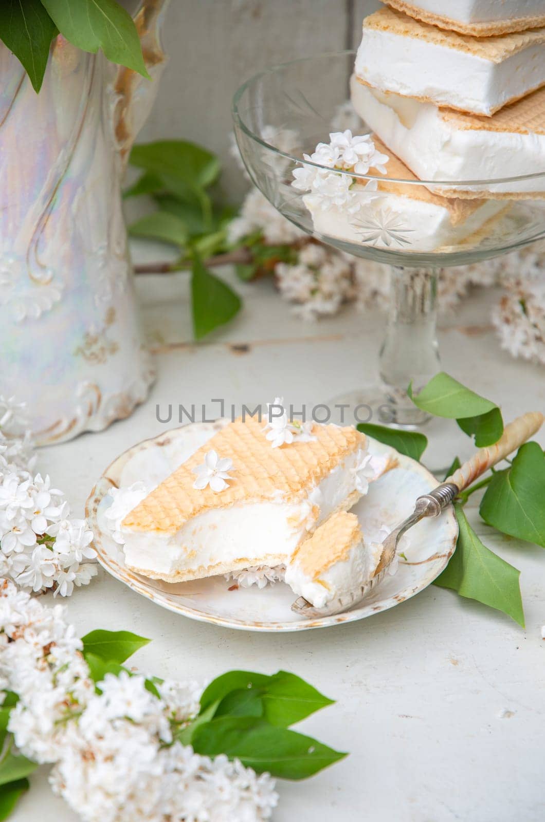 spring still life with a bouquet of white lilacs, a stack of waffle ice cream in a bowl and on a saucer, vintage ceramic dishes, high quality photo