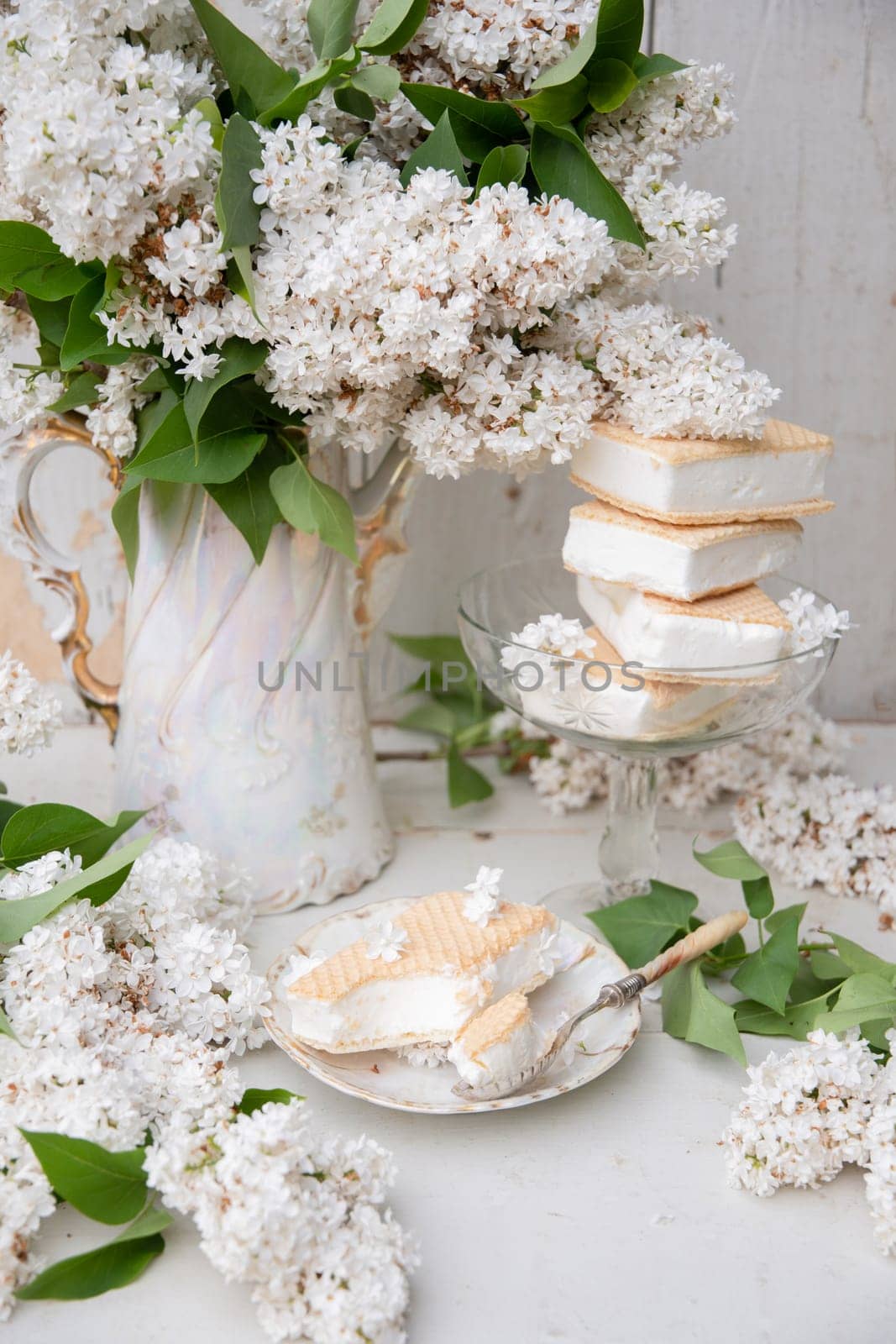 spring still life with a bouquet of white lilacs, a stack of waffle ice cream in a bowl and on a saucer, vintage ceramic dishes, high quality photo