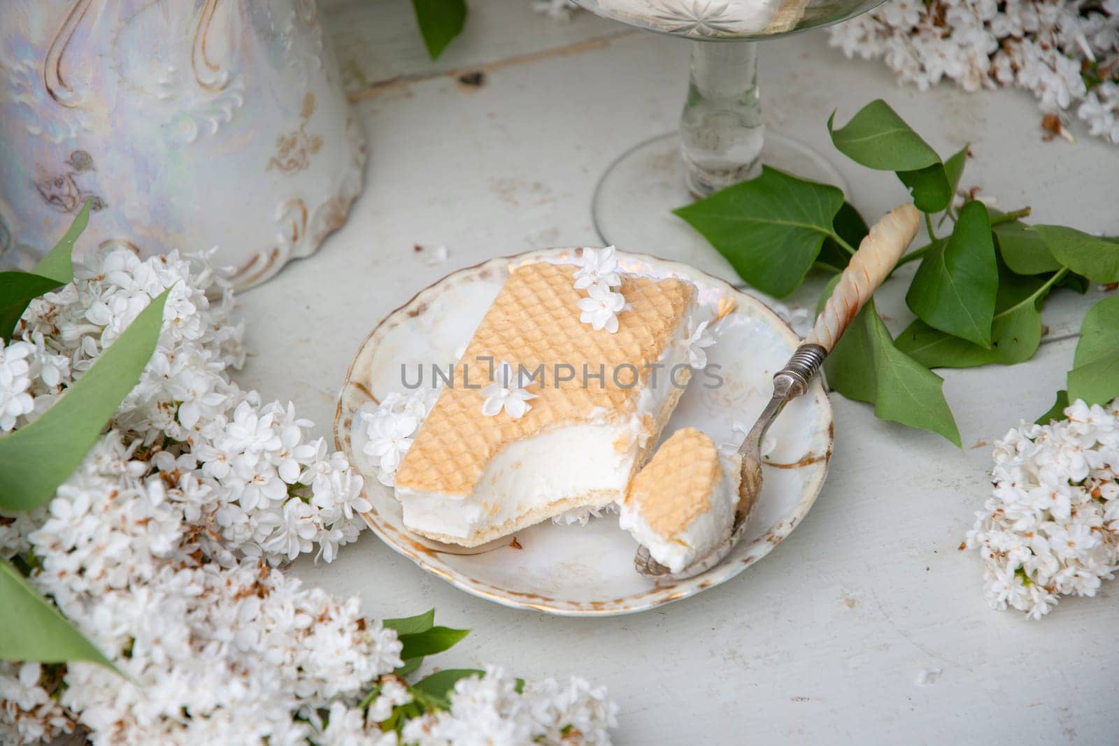 bitten waffle ice cream in a bowl and on a saucer, spring still life with a bouquet of white lilacs, antique porcelain tableware, romantic break for dessert, high quality photo