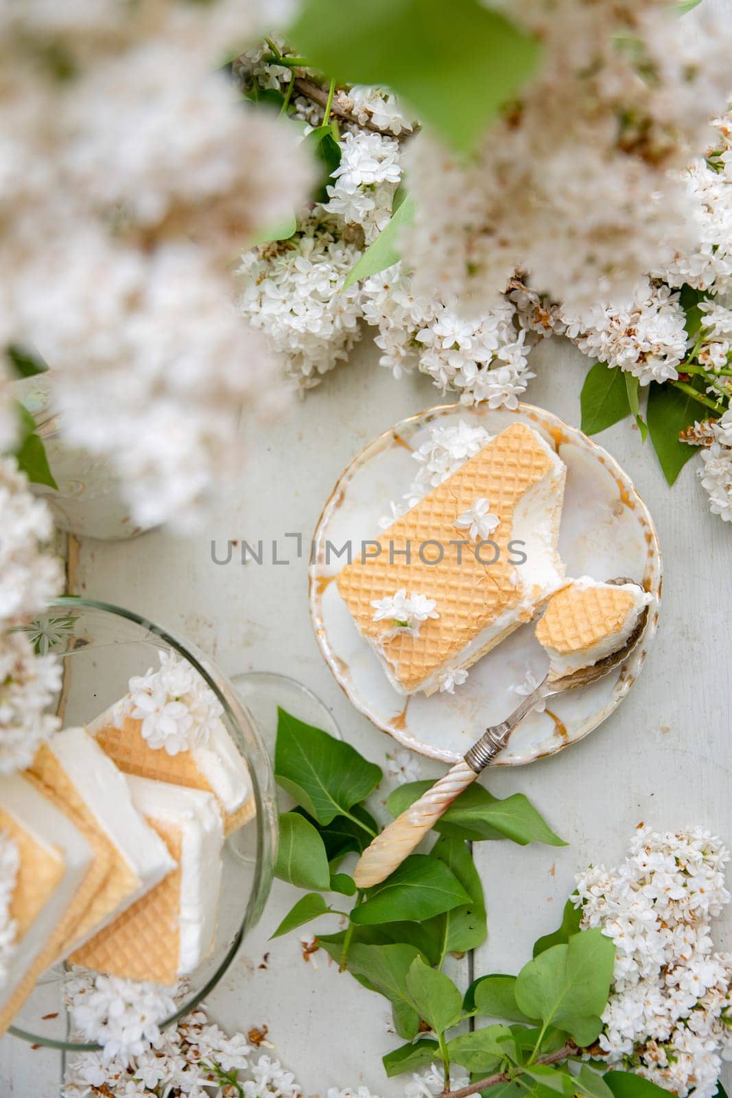 bitten waffle ice cream in a bowl and on a saucer, spring still life with a bouquet of white lilacs, antique porcelain tableware, romantic break for dessert, top view , high quality photo