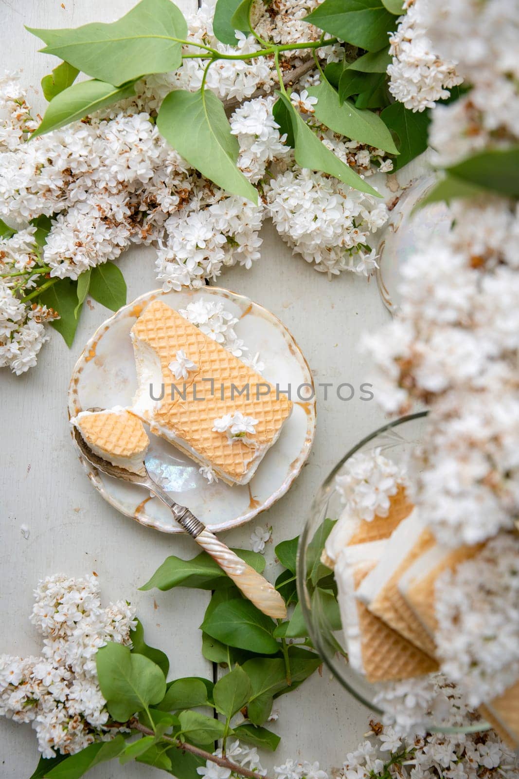 bitten waffle ice cream in a bowl and on a saucer, spring still life with a bouquet of white lilacs, antique porcelain tableware, romantic break for dessert, top view , high quality photo