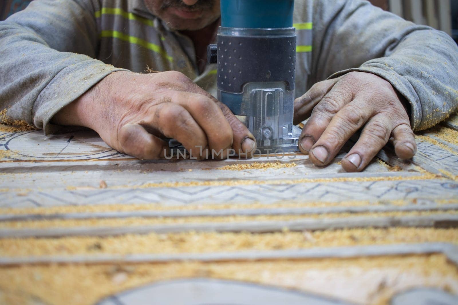 Close Up of Man Hands carving on wooden furniture. Carpenter using tool making Artistic Wood Carving. Producing an Ornament on Wood with Chisel and Hammer on a Panel of Wood by senkaya