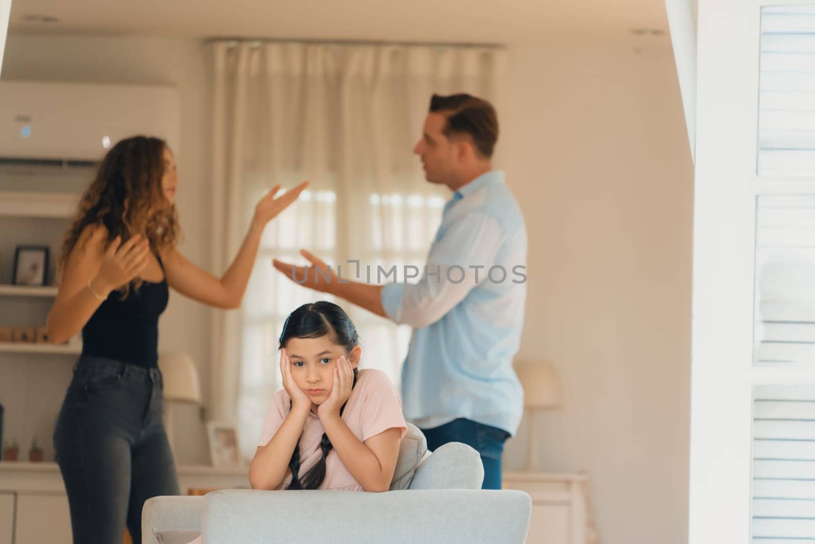 Annoyed and unhappy young girl look at camera, trapped in middle of tension by her parent argument in living room. Unhealthy domestic lifestyle and traumatic childhood develop to depression.Synchronos