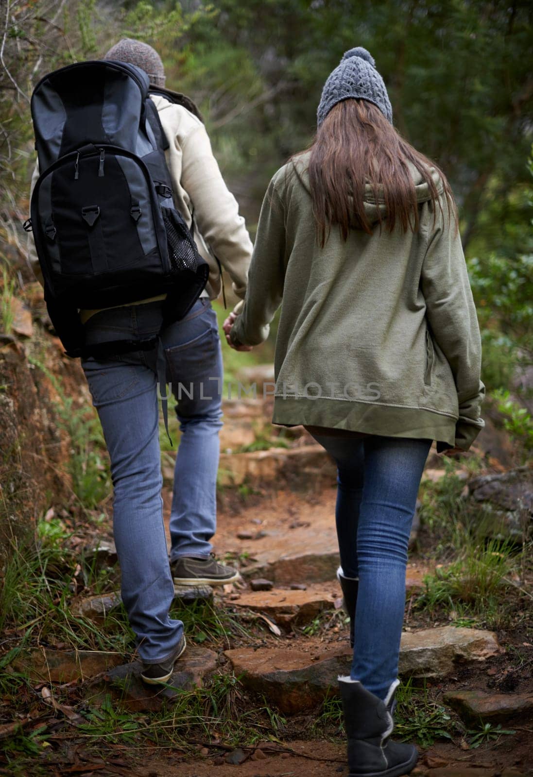 Couple, hiking in nature and holding hands for outdoor adventure and travel journey in a forest or eco woods. Back of People with love, support and walking or trekking in backpack on mountains path.